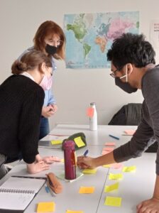 3 personnes collaborent et écrivent sur des post it autour d'une table