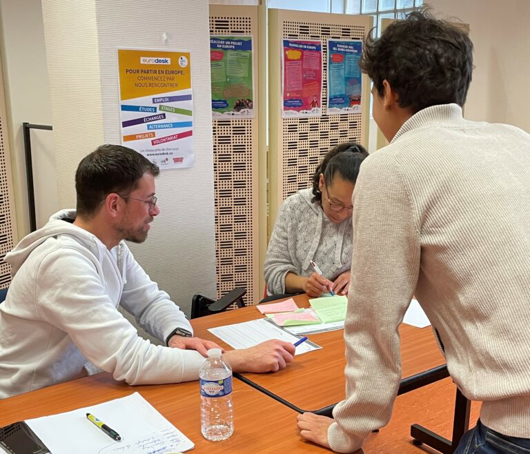 3 personnes travaillent autour d'une table sur du papier