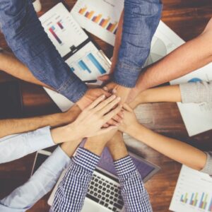 6 personnes joignent leurs mains au dessus d'une table