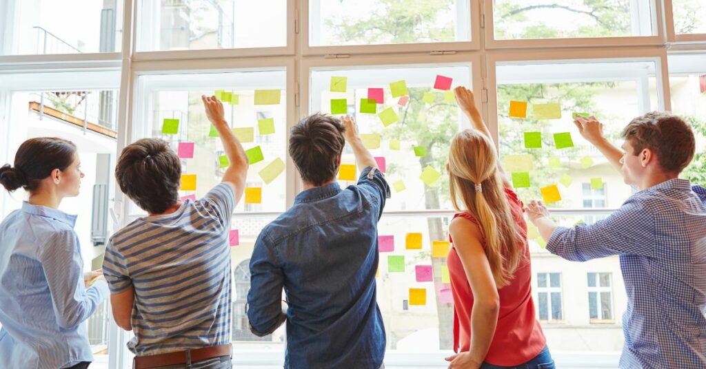 5 personnes collent des post-it sur des vitres