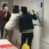 3 personnes debout collent des posts sur un tableau