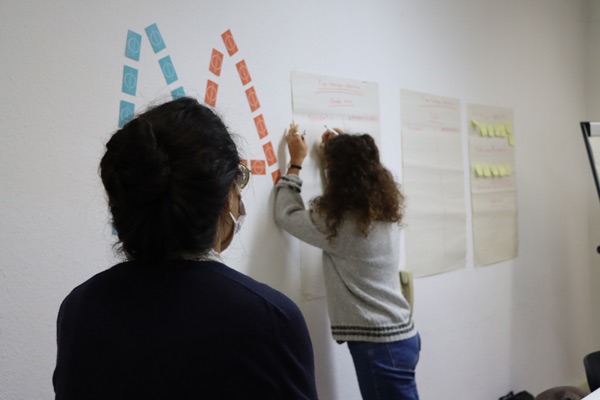 Photo de formation représentant une personne de dos en train d'écrire sur un paper board et une personne de dos en premier plan qui assiste à la formation