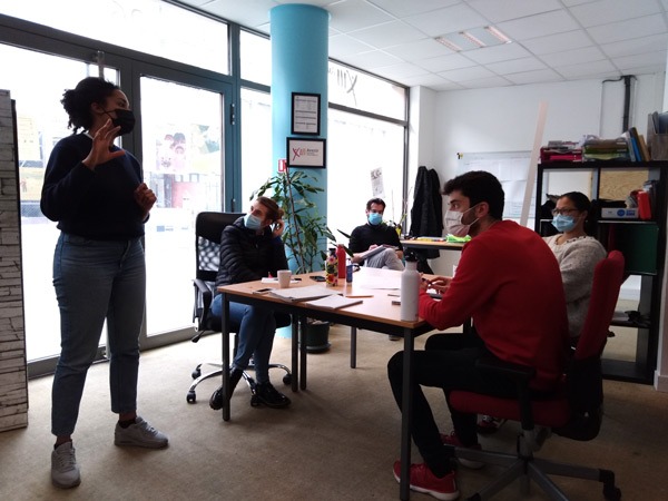 Photo d'un atelier : 4 personnes assises et une personne debout en train de parler