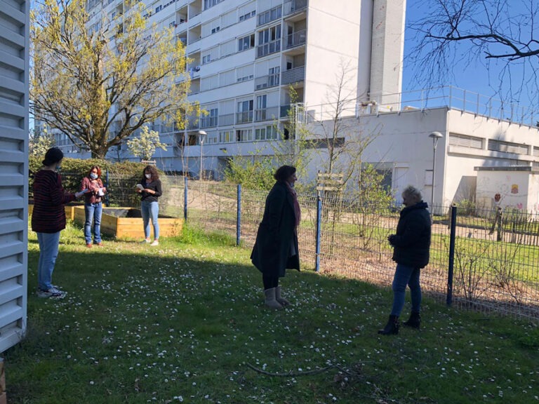 Photo d'un atelier animé en extérieur au sein d'un quartier. 5 participantes et une barre d'immeuble en arrière plan